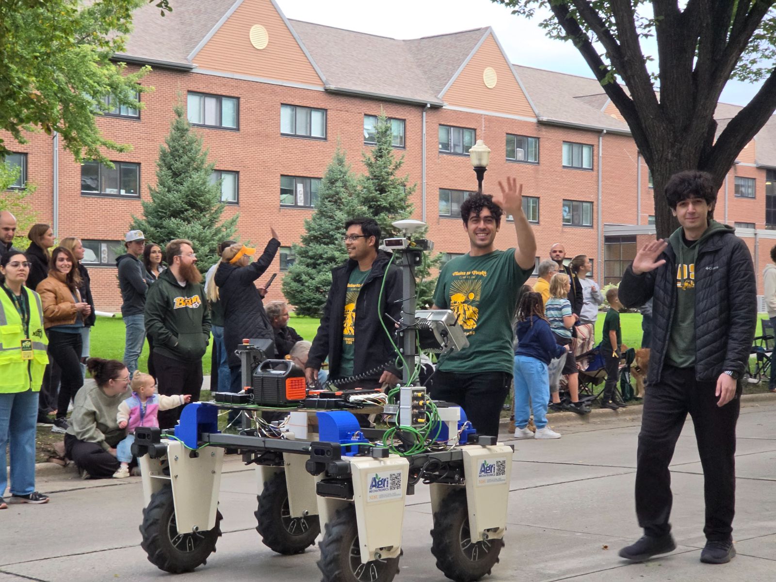 Lab members waving from the Homecoming parade with the UGV